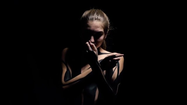 Beautiful girl in black body art appears out of the darkness