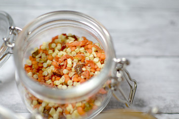 glass jar with chopped vegetables and spices on a wooden table