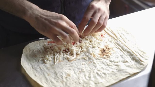 Lavash rolls with cheese and tomatoes. Сhef turns the pita with stuffing. Healthy breakfast concept.