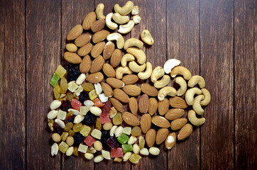 Heart of almonds, cashews and dried fruits on a brown wooden table