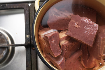Beef heart in a pot of water on a gas stove
