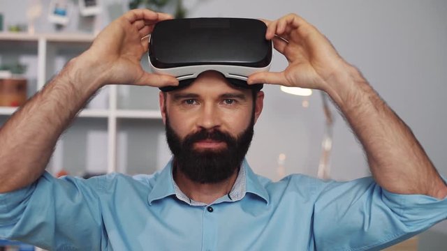young man wearing virtual reality glasses sit on the sofa home feel happy smiling innovation looking modern entertainment gadget close up face new tech visual beard game hipster slow motion