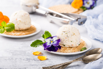 Vanilla ice cream scoop with edible flowers pansy. Summer food concept.