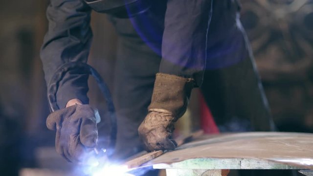 Hands of a workman in protective gloves holding wood plank to adjust a cutting line on metal construcion. Cutting with metal oxy acetylene cutting torch. Dangerous work.