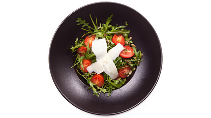 Green salad made with arugula, tomatoes, cheese mozzarella and sesame on black plate, on white.isolated