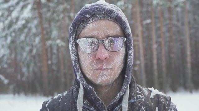a frozen man with glasses in the winter forest, after a snow storm, covered with snow