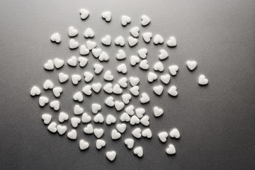 A lot of white medicine pills in the form of hearts on a grey