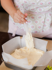 Female hands spreads the dough over the pie in a baking dish. Cooking process on kitchen.