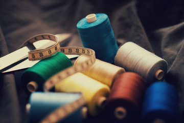 Pile of colorful spools of threa, scissors and measuring meter 