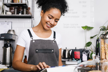 Smiling beautiful waitress using digital tablet in cafe - obrazy, fototapety, plakaty