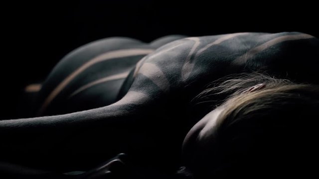 The girl in black body art lies on the floor and moves the booty