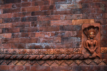 ceglana ściana świątyni w nepalu ze zdobnym detalem oraz figurką