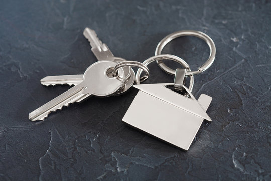 estate concept with key, keychain with house symbol, stone background