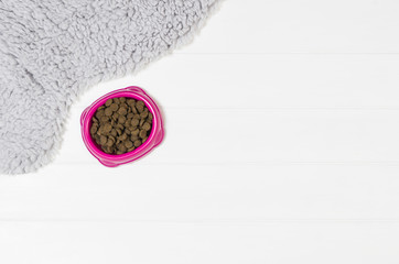 Dry dog pet food in bowl on white wooden background top view. Pet feeding concept backgrounds with copy space. Photograph taken from above.