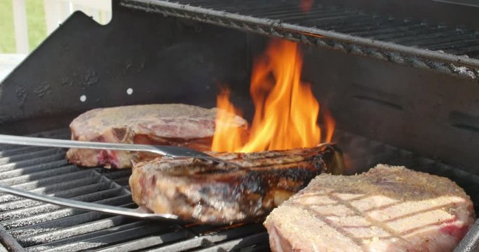 Bone In Ribeye Steaks Thick on Grill with Flames Flipping Them, 4K