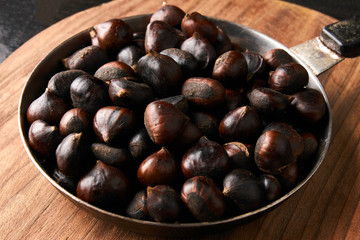 Chestnuts in a pan on wooden board