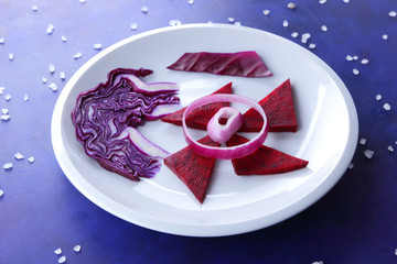 Violet cabbage, onions and red beets on a white plate, vegetables in space, vegetables on the ultraviolet background, large salt, purple onions, cabbage on a dark blue background, pop art
