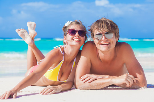 picture of happy couple in sunglasses lying on the beach