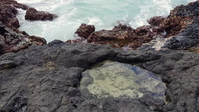 huge wave hits the volcanic rocks.