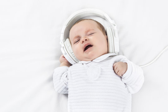Cute baby in headphones over white background