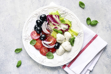 Italian salad caprese with black olive and salad leaves.Top view.