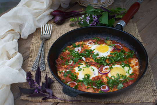Shakshuka or fried eggs with tomatoes.