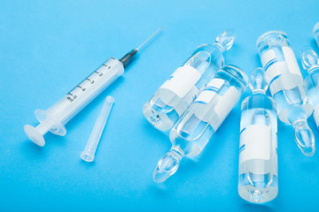Ampoules and a syringe on a blue background, top view.