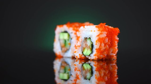 Sushi rolls rotated over black background. Sushi roll set with tuna, vegetables and flying fish roe closeup. 4K UHD video footage. 3840X2160