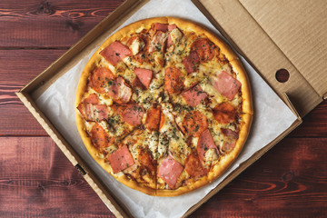 Just delivered pizza in box on wooden table, top view