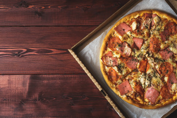 Just delivered pizza in box on wooden table, top view