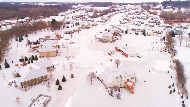 Idyllic neighborhoods in the grip of Winter, homes lightly frosted with snow and ice, aerial view.