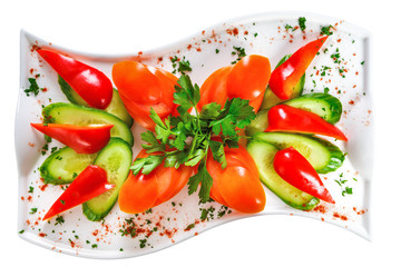 Salad of tomatoes, cucumbers and parsley on a plate, sprinkled with spices