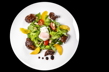 A dish of meat,lettuce, oranges, nuts and chicken eggs, drizzled with sauce in bowl on black background