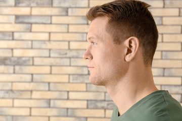 Young man on brick wall background. Hearing problem