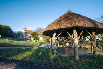 St Peters Church and thatched village well. East Marden, West Sussex, UK