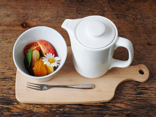 Teapot with assortment of fruits, on wooden table