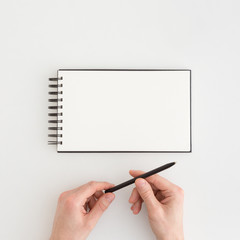Man opening a pen before writing in book with white cards. Mock up.