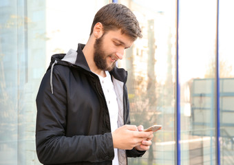Fototapeta premium Portrait of trendy hipster man using mobile phone outdoors