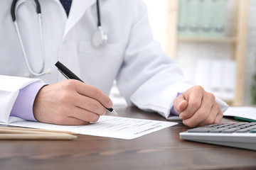 Doctor filling in insurance form at table