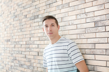 Portrait of young man in casual clothes on brick wall background