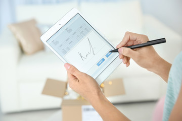 Woman appending signature after receiving parcel indoors