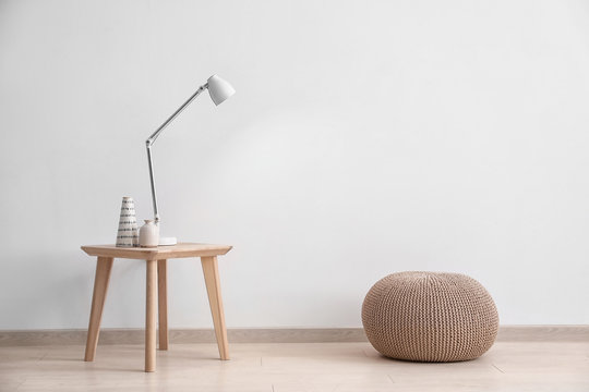 Living room interior with wooden table and pouf near wall