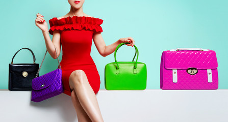 Woman with red dress sitting with many colourful purses.