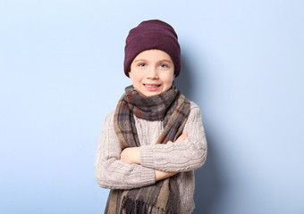 Cute little boy in warm clothing on color background. Ready for winter vacation © Africa Studio
