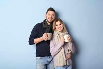 Fototapeta premium Young couple in warm clothing on color background. Ready for winter vacation