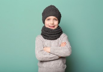 Cute little boy in warm clothing on color background. Ready for winter vacation