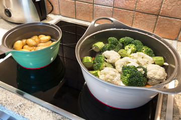Two stew pots with baby potatoes, broccoli and cauliflower.