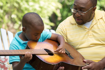 Father teaaching his his son to play the guitar.