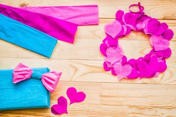valentine day concept. a wreath decorated with purple and pink crepe paper hearts and gift with a bow