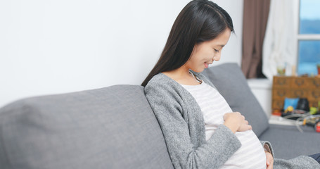 Pregnant woman looking at her tummy at home